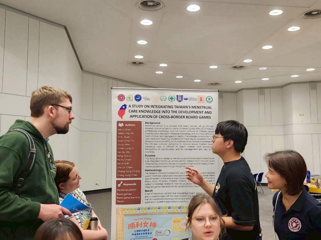 護理系學生傅冠鈞向詢問的國際友人熱情介紹「順利女神生理期照護」桌遊之設計